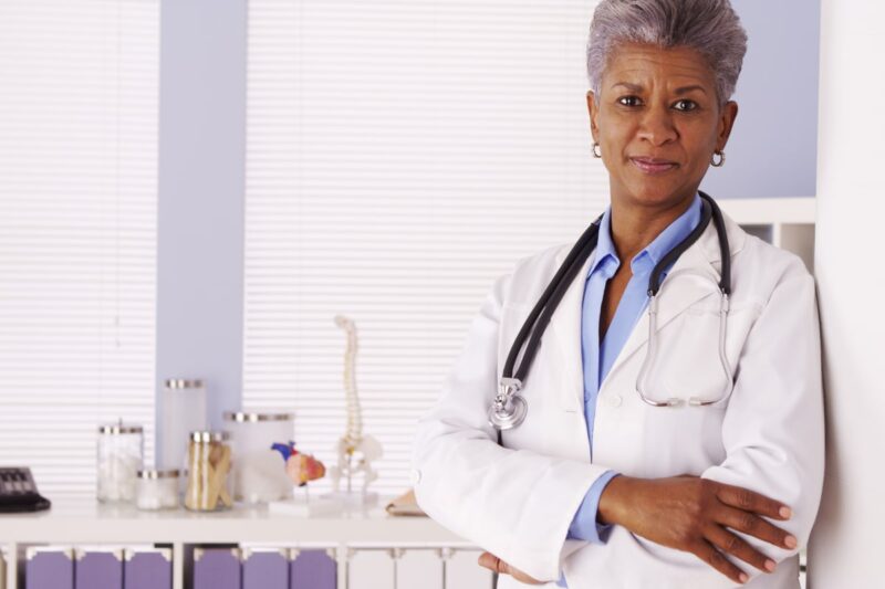 Older black female doctor in white coat with stethoscope